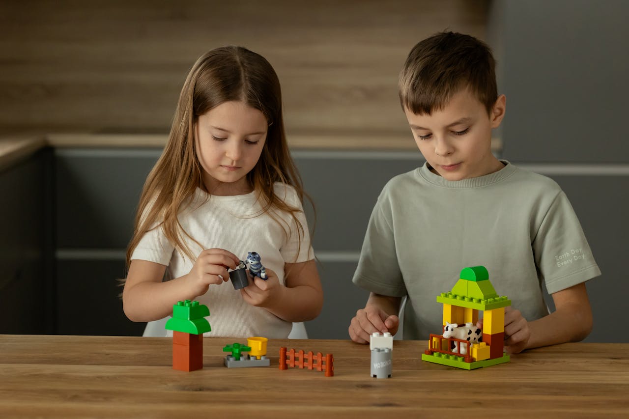 Two young children playing and assembling toys on a wooden table, fostering creativity.